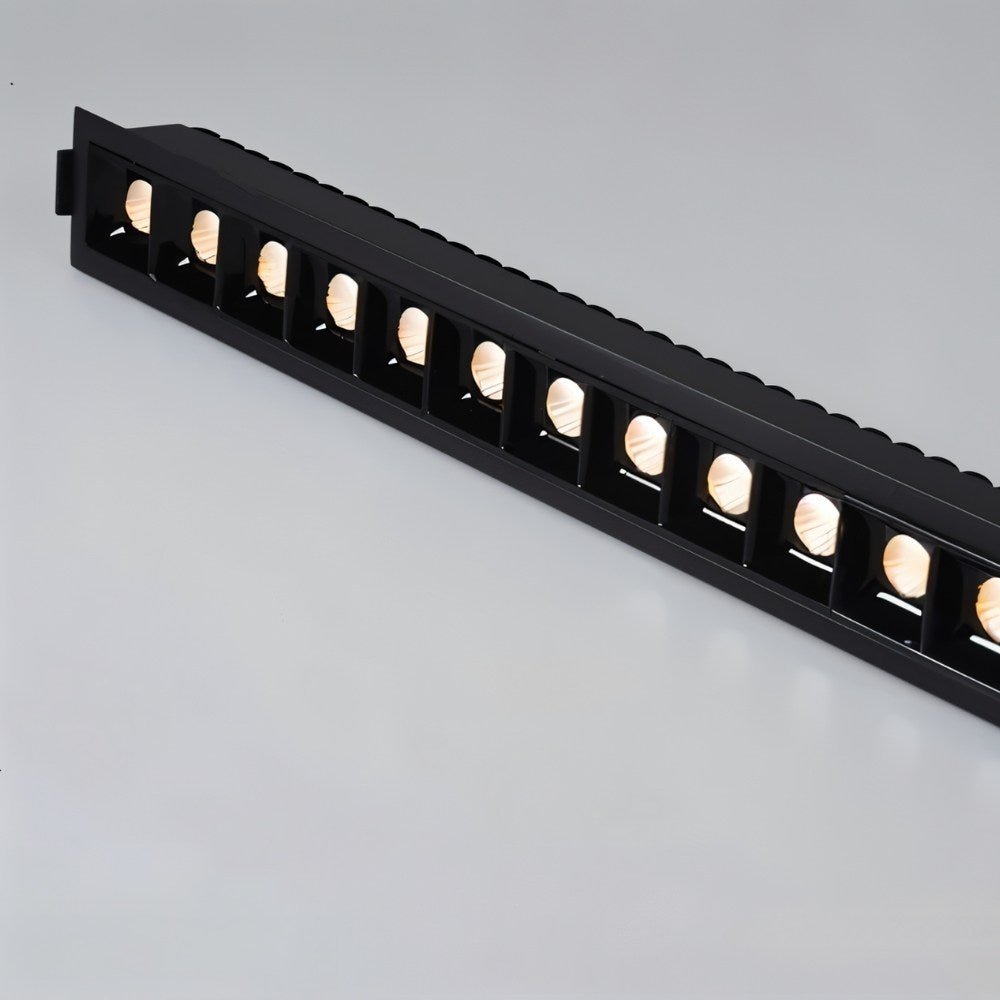 Clérachic black multi-head linear downlight lit warm, a row of square reflectors in a black trim with a ribbed back.