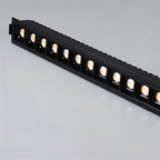 Clérachic black multi-head linear downlight lit warm, a row of square reflectors in a black trim with a ribbed back.