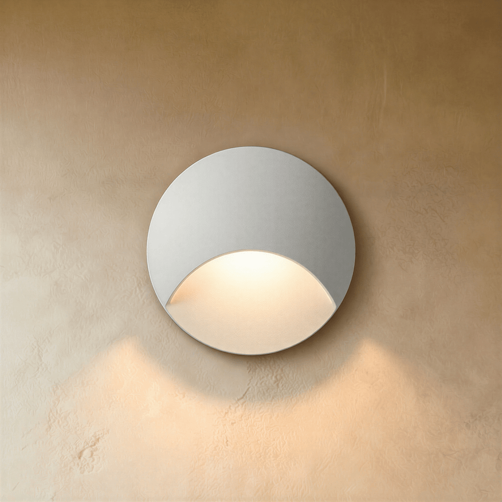 Clérachic recessed step light in white with a crescent-cut face, warm glow washing softly down a plaster stairwell wall.