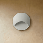 Clérachic recessed step light in white with a crescent-cut face, shown unlit on a softly textured plaster wall.