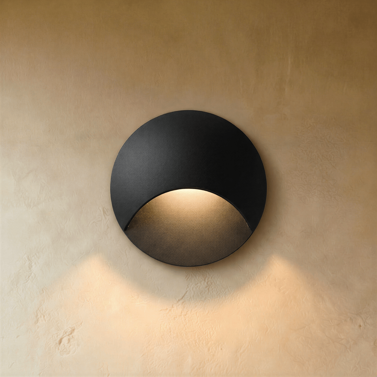 Clérachic recessed step light in matte black with a crescent-cut face, warm glow washing down a plaster stairwell wall.