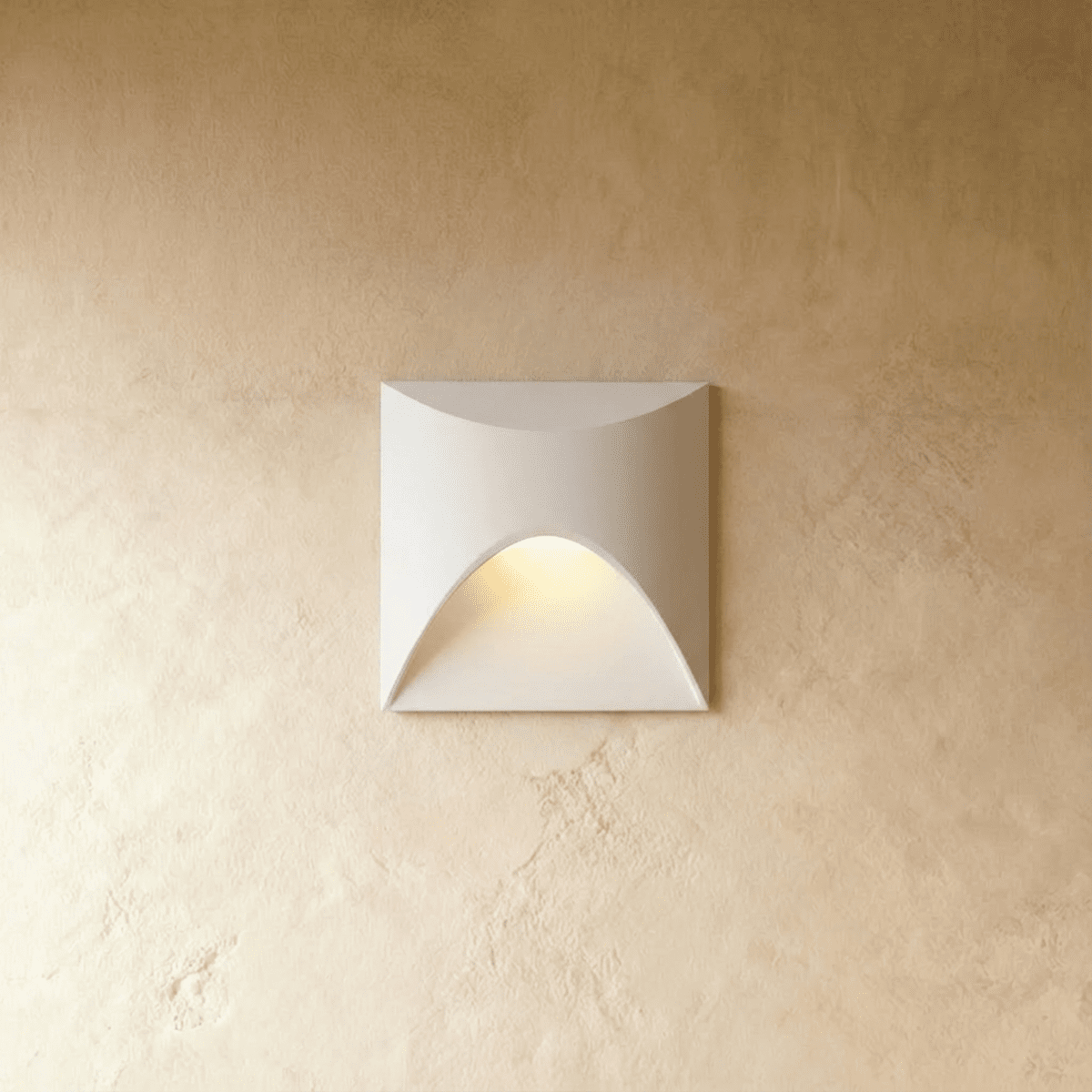Clérachic recessed step light in white with a square face and arched cutout, warm glow spilling onto a plaster wall.