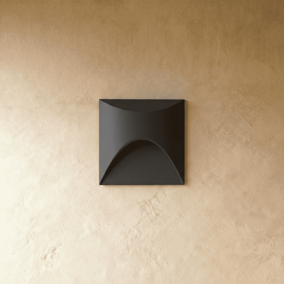 Clérachic recessed step light in matte black with a square face and arched cutout, shown unlit on a plaster wall.