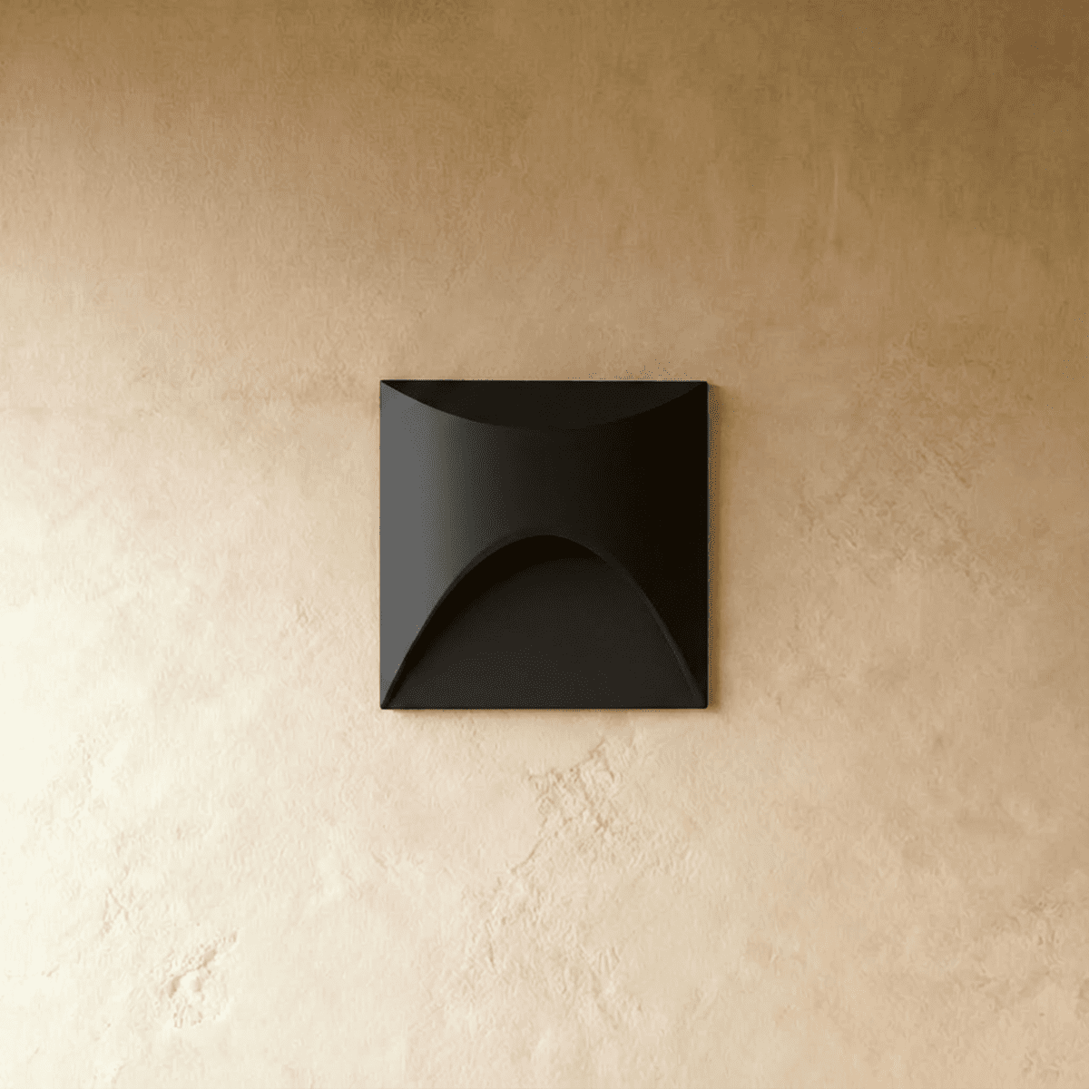 Clérachic recessed step light in matte black with a square face and arched cutout, seen unlit against a plaster wall.
