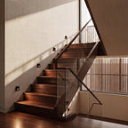 Clérachic step lights recessed along a walnut staircase wall, casting a warm glow across each dark wood tread.