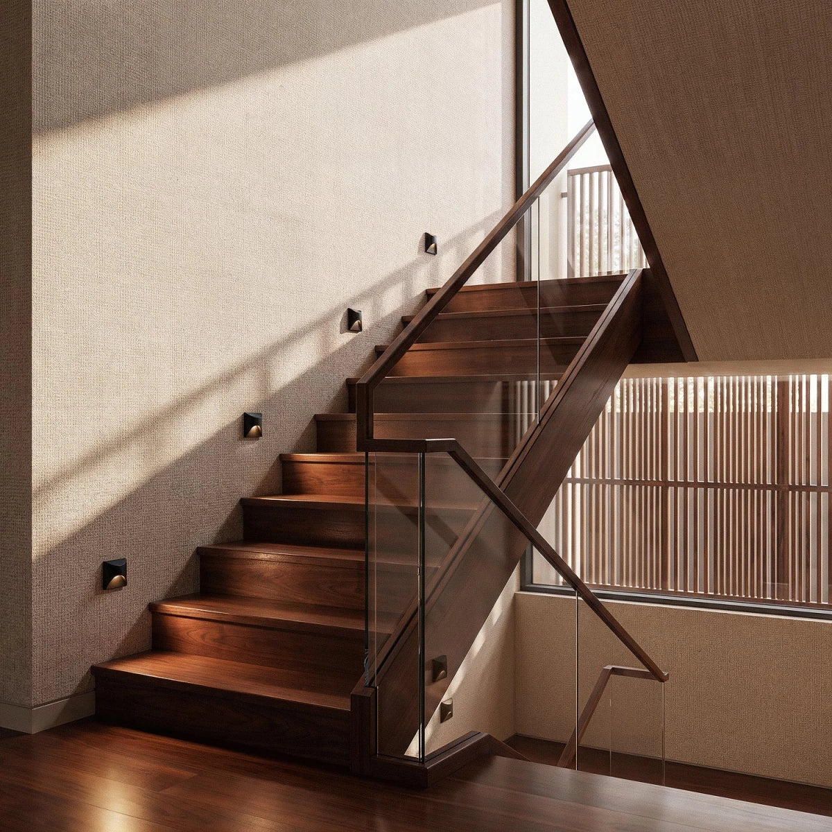 Clérachic step lights recessed along a walnut staircase wall, casting a warm glow across each dark wood tread.