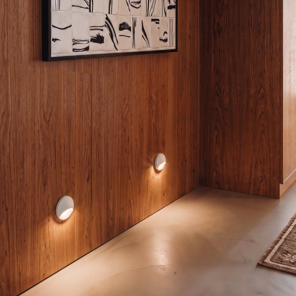 Clérachic recessed step lights in white set low on a walnut-panelled wall, warm glow beneath a framed textile artwork.