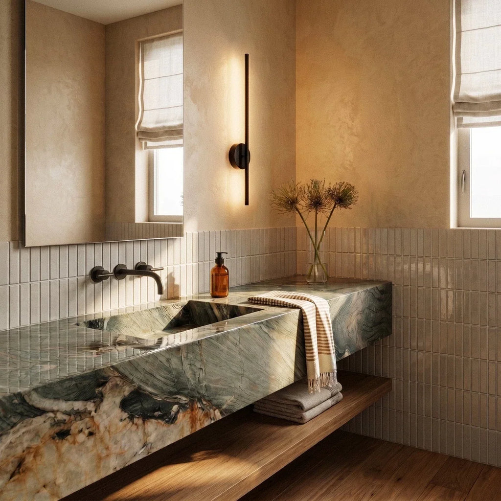 Clérachic slim black wall lamp glowing beside a window and a marble basin with a wall tap, on warm plaster walls.