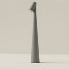 Clérachic cone desk lamp in grey, tapering from a wide base up to the tilted head.
