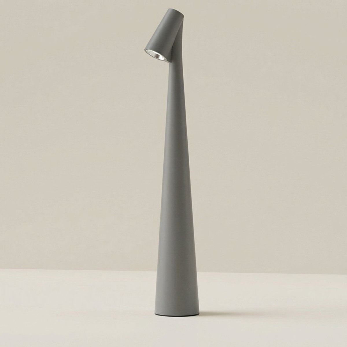 Clérachic cone desk lamp in grey, tapering from a wide base up to the tilted head.