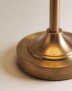 Clérachic brushed gold lamp base close up, showing the stepped round foot and the slim metal stem with its fine metal grain.