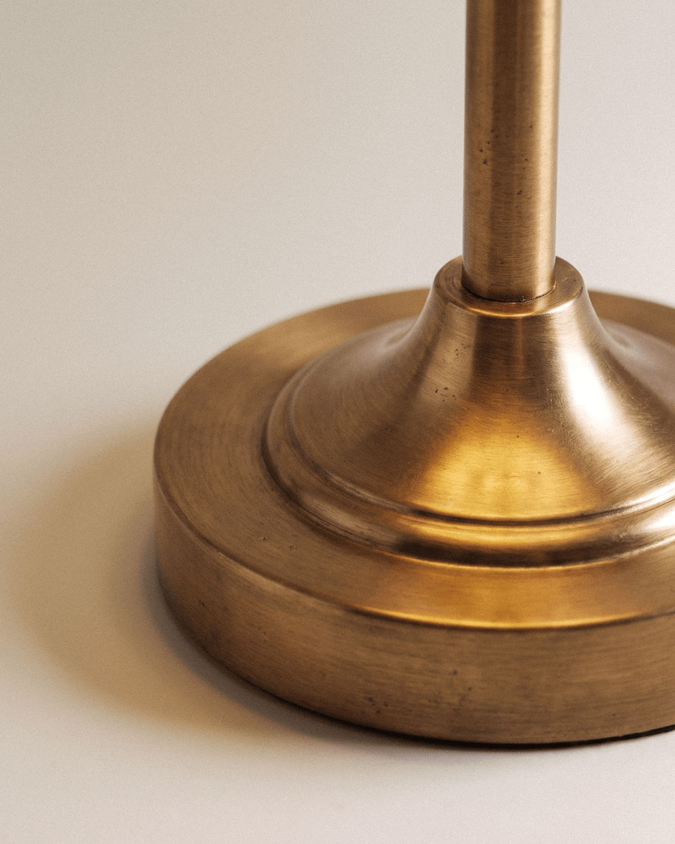 Clérachic brushed gold lamp base close up, showing the stepped round foot and the slim metal stem with its fine metal grain.