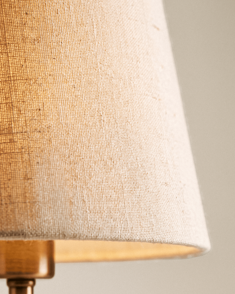 Clérachic tapered white fabric lamp shade close up, showing the woven texture and the warm glow of the light behind it.