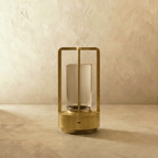Clérachic brass table lamp switched off, showing the slim open frame, clear glass cylinder and round base with a charging port.
