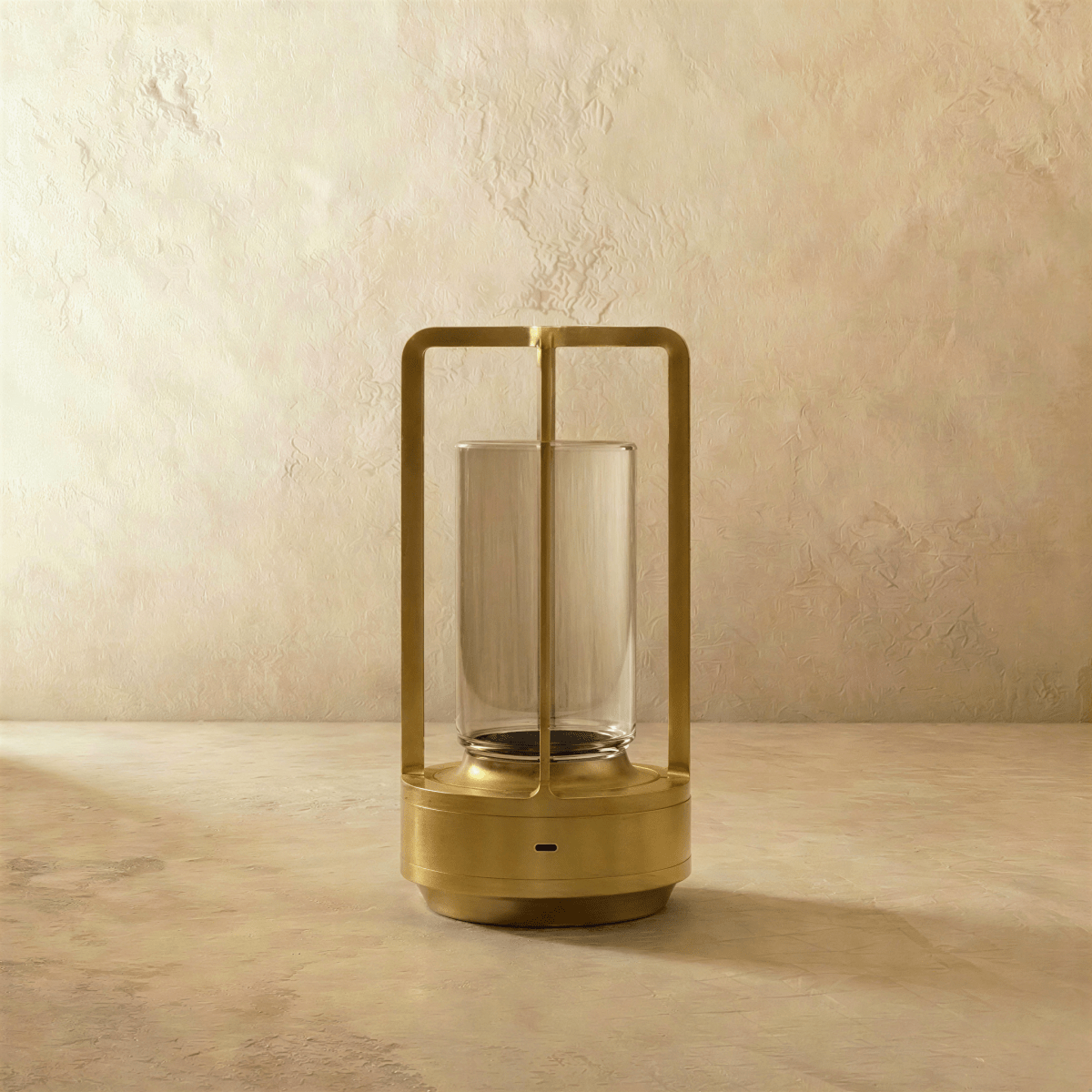 Clérachic brass table lamp switched off, showing the slim open frame, clear glass cylinder and round base with a charging port.