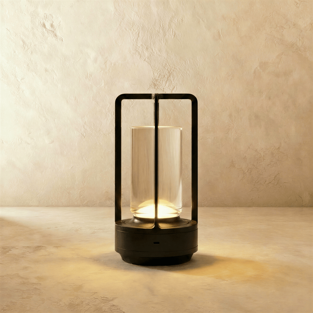 Clérachic black table lamp with an open metal frame around a lit glass tube, standing on a pale stone-effect surface.
