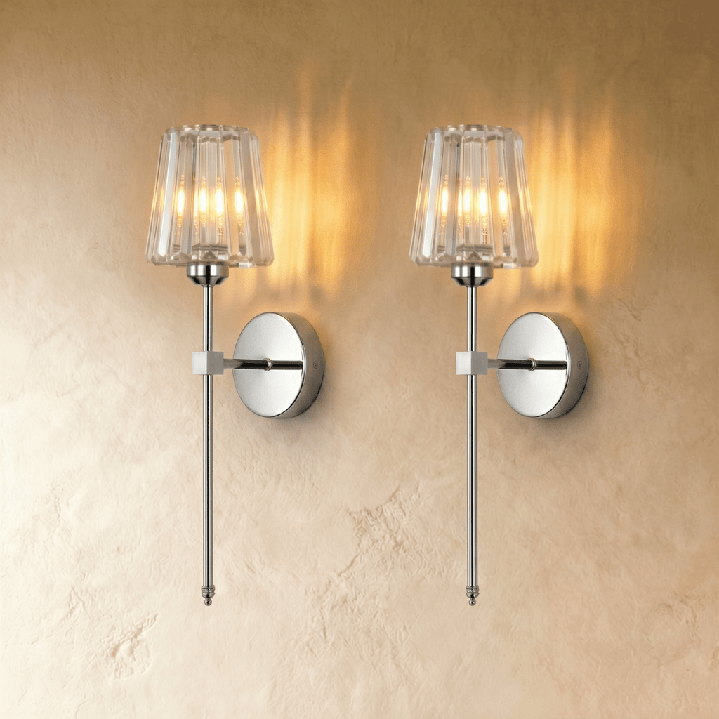 Clérachic pair of polished silver wall sconces with fluted glass shades, glowing warm side by side on a plaster wall.