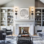 Clérachic pair of black wall sconces with faceted glass shades flanking a round art print above a white marble fireplace.