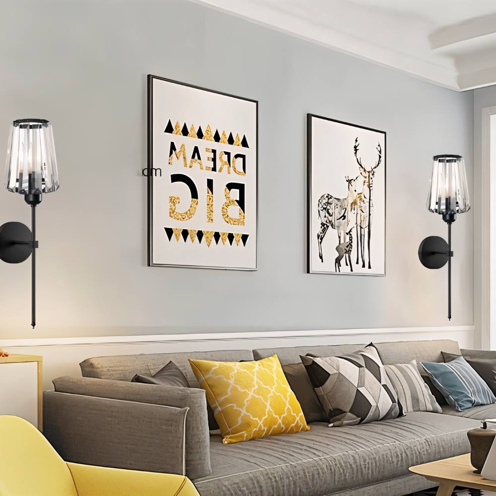 Clérachic pair of black wall sconces with fluted glass shades on a grey living room wall above a sofa and framed prints.