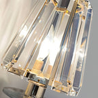 Close detail of a Clérachic wall sconce shade, showing the faceted clear glass panes, candle-style bulbs and brass-tone fittings.