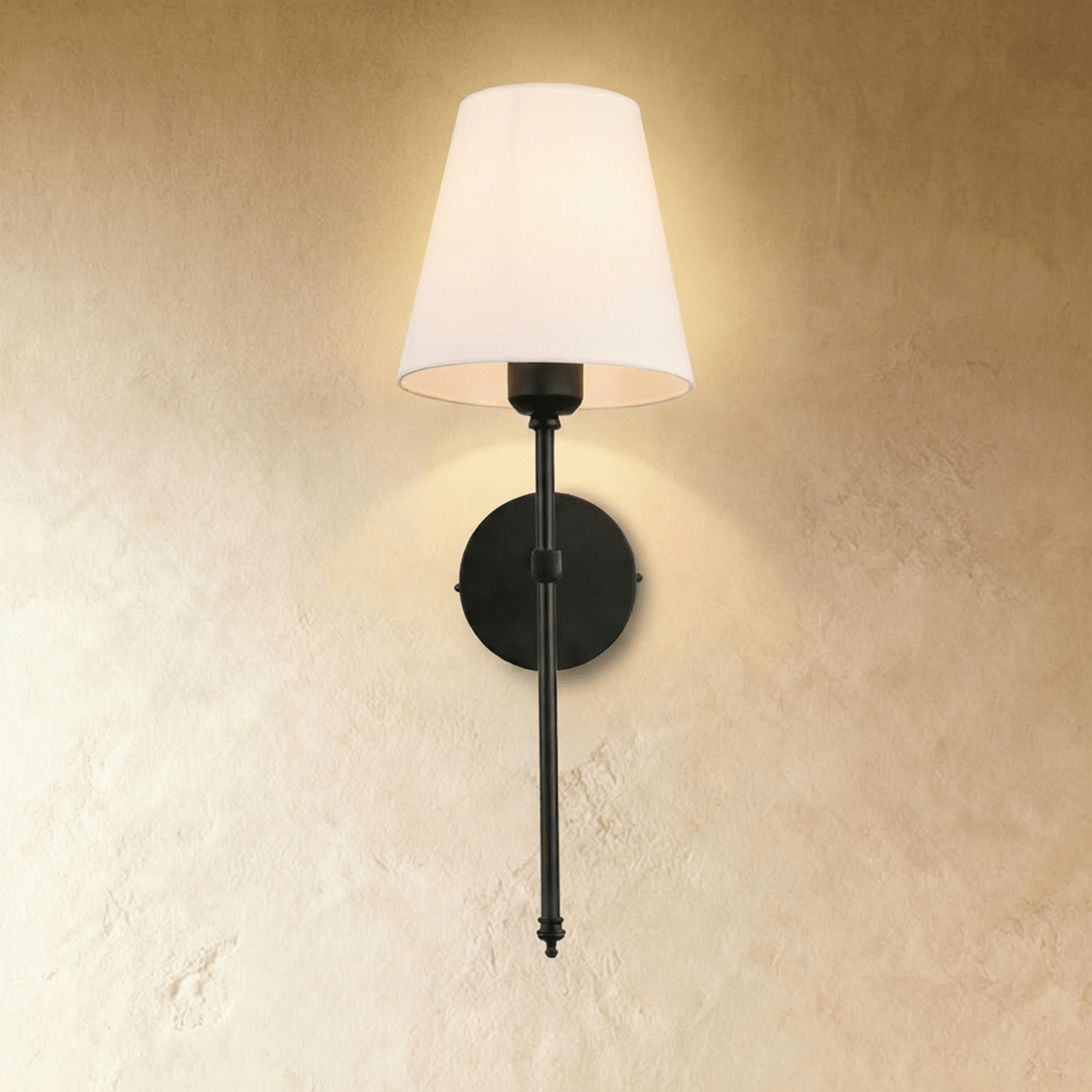 Clérachic black wall sconce with a white tapered fabric shade on a slim rod and round backplate, glowing on a limewash wall.