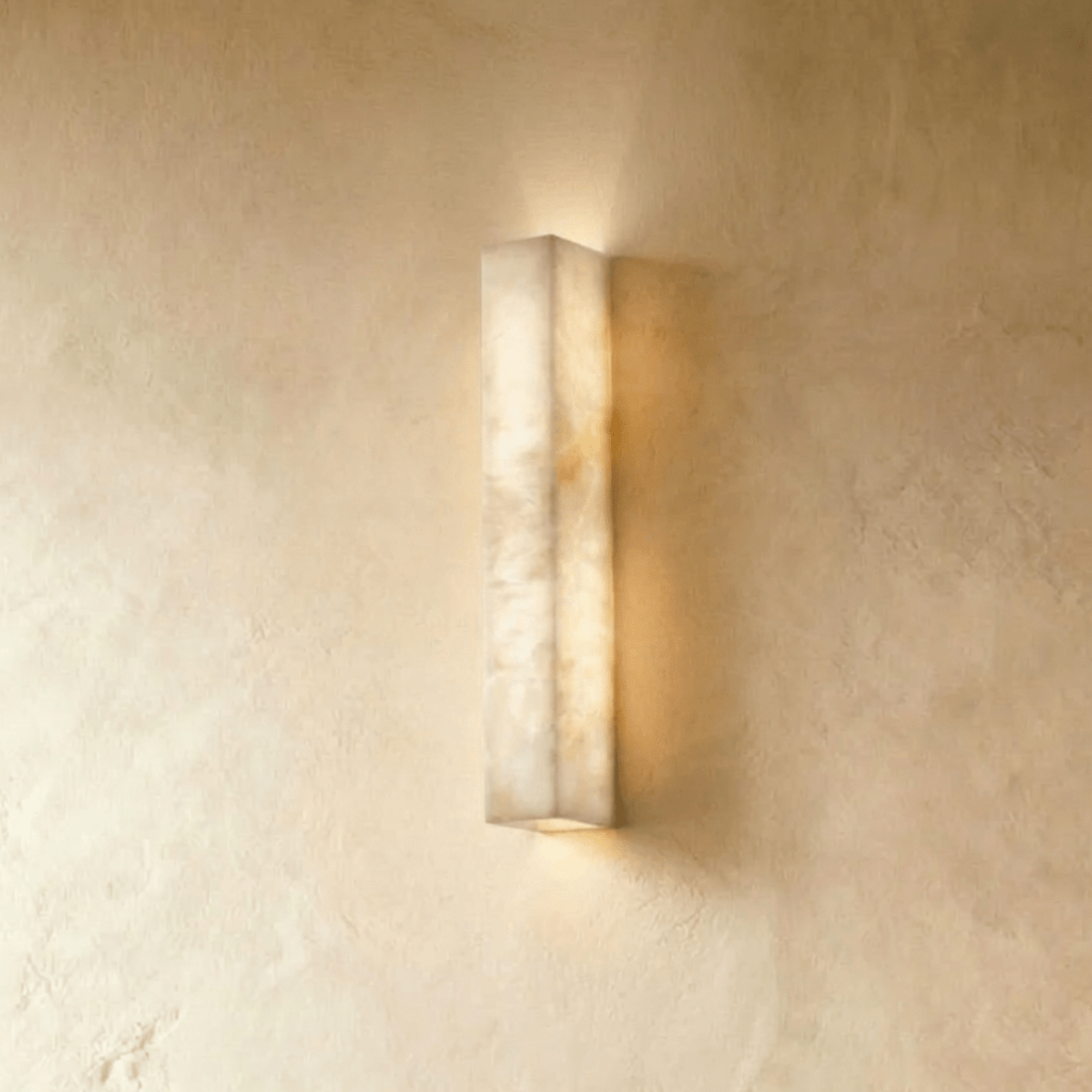 Clérachic slim alabaster bar wall light, lit, glowing up and down a limewashed wall in warm cream tones