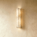 Clérachic slim alabaster bar wall light, lit, glowing up and down a limewashed wall in warm cream tones