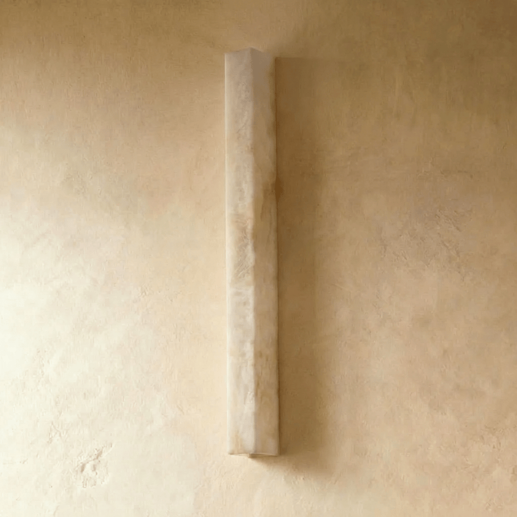 Clérachic long alabaster bar wall light switched off, the pale veined stone sitting flat against a limewashed wall
