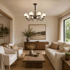 Eight white globes lit on this Clérachic chandelier above a living room with a cream sofa, linen armchairs and a low timber table.