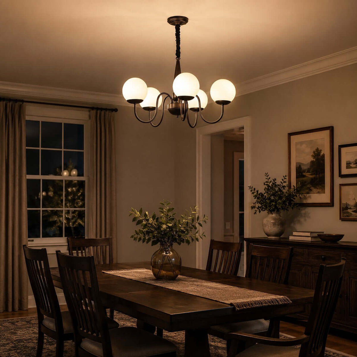 In evening light, a Clérachic chandelier with warm white globes hangs above a dark wooden dining table and slatted chairs.