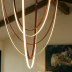 Close-up of the Clérachic leather chandelier's cognac leather loops glowing warm white in nested swags.