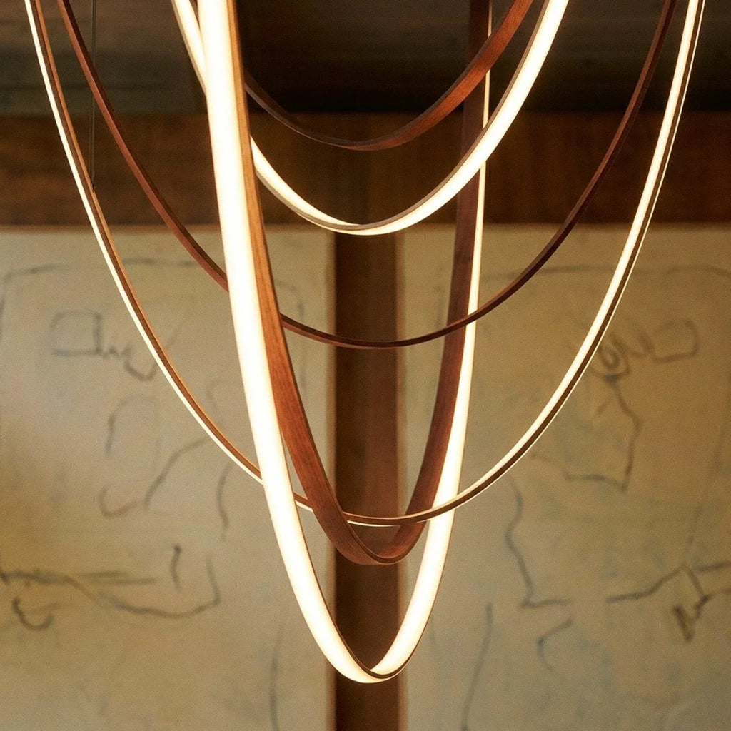 Close-up of the Clérachic leather chandelier's nested leather loops glowing warm white against a charcoal sketch.