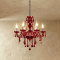 Clérachic deep red crystal chandelier with six candle-style lights, curved arms and faceted drops, hung on a chain.