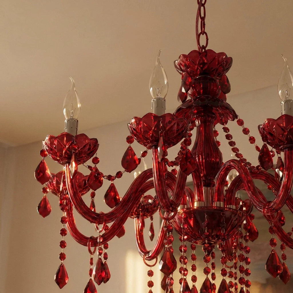 Detail of a Clérachic red crystal chandelier with candle bulbs, ribbed floral cups, curved arms and beaded drops in warm light.