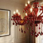 Close-up of the Clérachic red crystal chandelier showing lit candle bulbs, a diamond-cut glass column and hanging red drops.