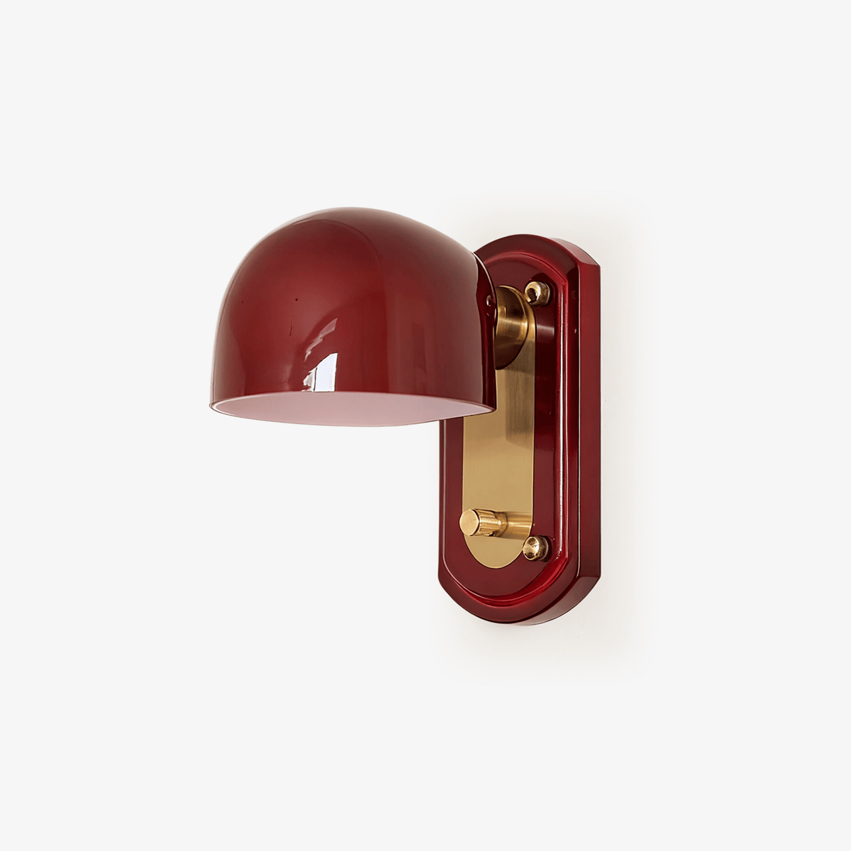 A Clérachic wall light on a plain white backdrop, with a deep red glass dome on a brass arm and a red oval backplate with a gold panel.