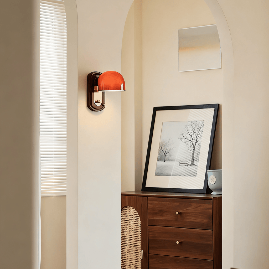 Small in a wider view, this Clérachic wall light is lit beside an arched doorway, with a framed print above a walnut and rattan cabinet.