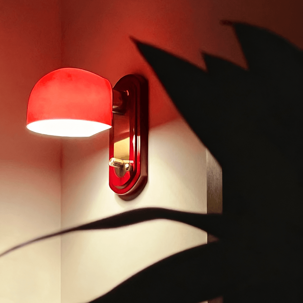 Lit dome of this Clérachic wall light glowing bright red, with the shadow of a large plant leaf falling across the wall.