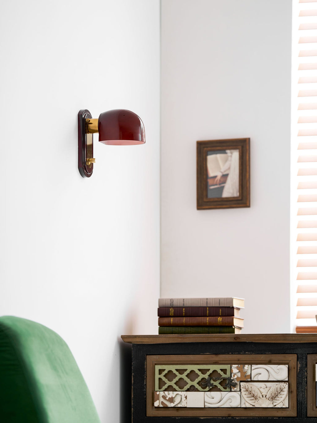 Unlit Clérachic wall light on a white wall above a green chair and a painted cabinet, with a framed picture to the right.