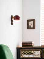 Unlit Clérachic wall light on a white wall above a green chair and a painted cabinet, with a framed picture to the right.