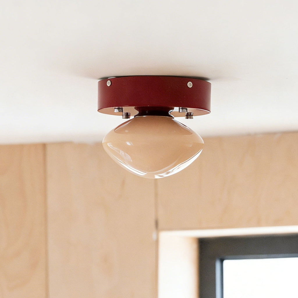 Red-canopied Clérachic flush mount with a beige dome, hanging beside a birch plywood wall and a window.