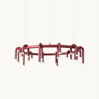 Red ring chandelier with arched tubular heads hanging below the frame, this Clérachic piece shown on a plain white backdrop.