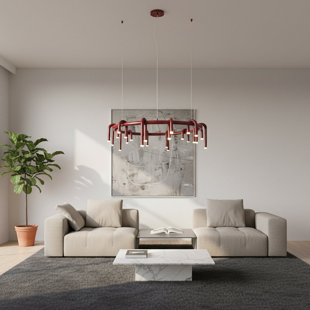 A red Clérachic ring chandelier above a cream sofa and a white marble coffee table, in a pale room with a large abstract artwork.
