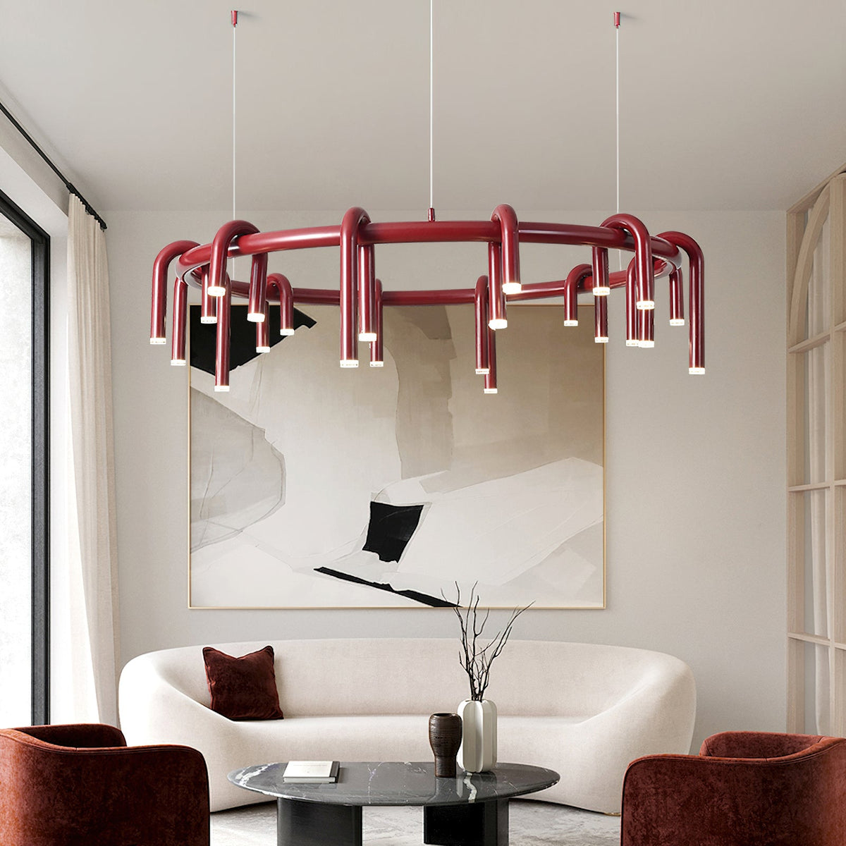 Clérachic ring chandelier in red above a curved cream sofa, with rust-red armchairs and a large abstract painting behind.