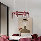 Clérachic ring chandelier in red above a round white table with burgundy chairs, beneath a framed portrait artwork.