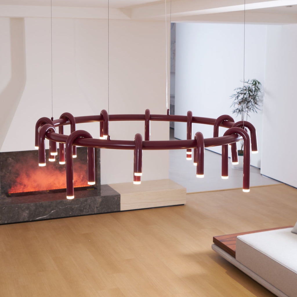 A wide red Clérachic ring chandelier seen from a low angle, with the arched heads and slim wires visible beside a fireplace.