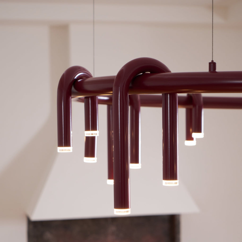 Close view of the arched red tubes of this Clérachic chandelier, each ending in a frosted light cap beneath the ring.