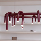 Close angled view of the red ring and its looping tubes on this Clérachic chandelier, with white shelves behind.