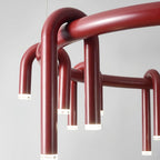 Close view of the red ring and arched tubes on this Clérachic chandelier, with frosted light caps at each tip.