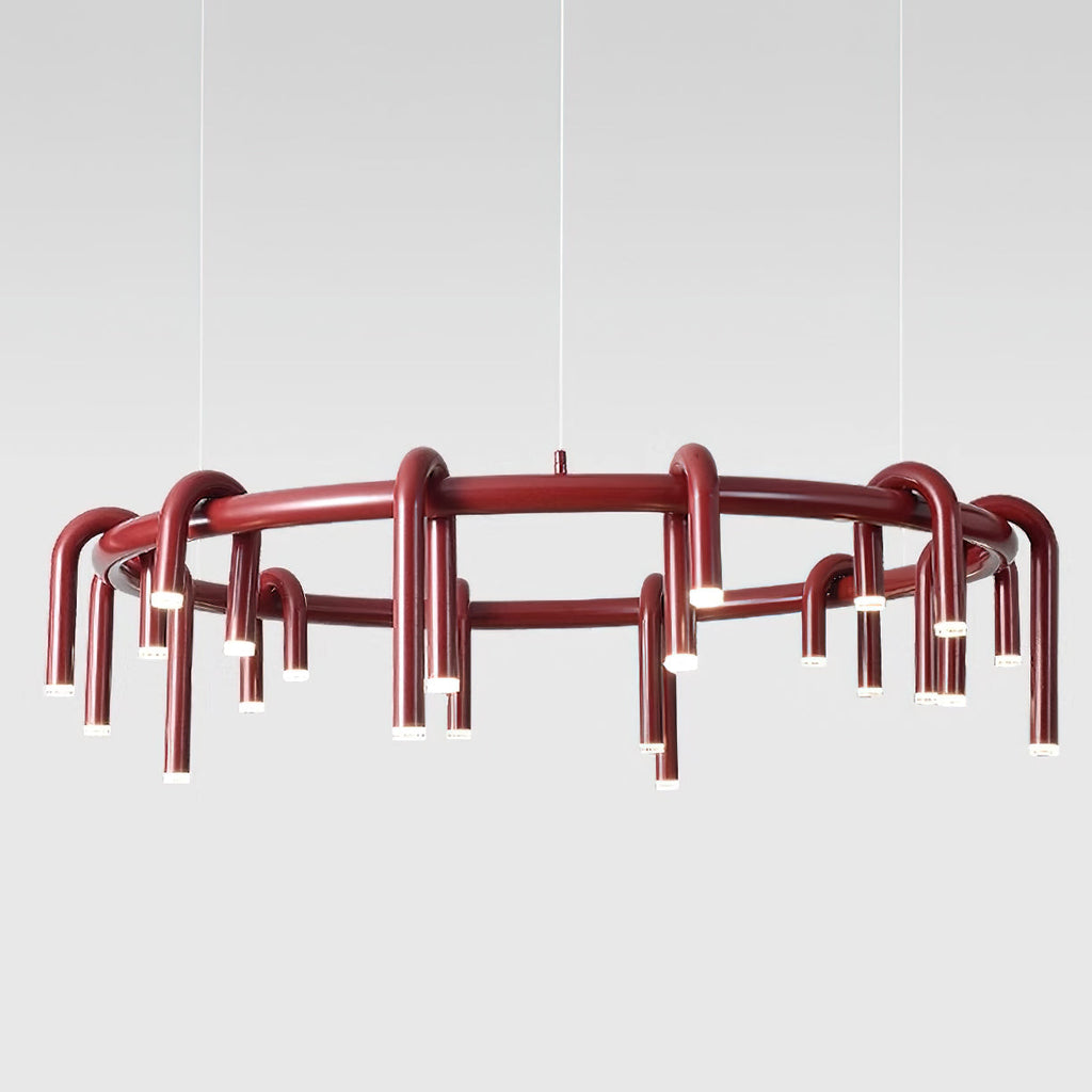 Red Clérachic ring chandelier photographed in front of a pale grey backdrop, with thin wires and arched tubes around the frame.